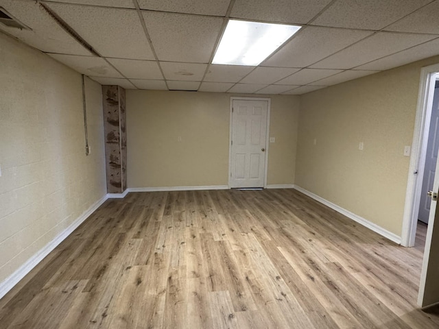 basement with a paneled ceiling and light hardwood / wood-style floors