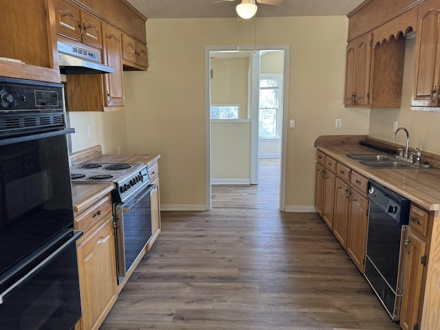 kitchen with sink, black appliances, a textured ceiling, and light hardwood / wood-style floors