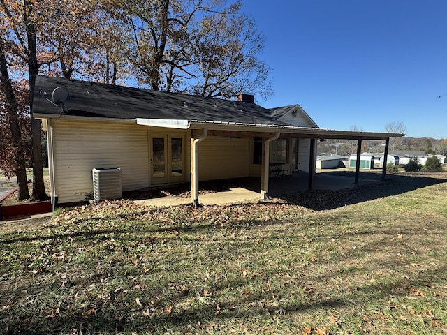 view of property exterior featuring a lawn, a patio area, french doors, and central AC unit