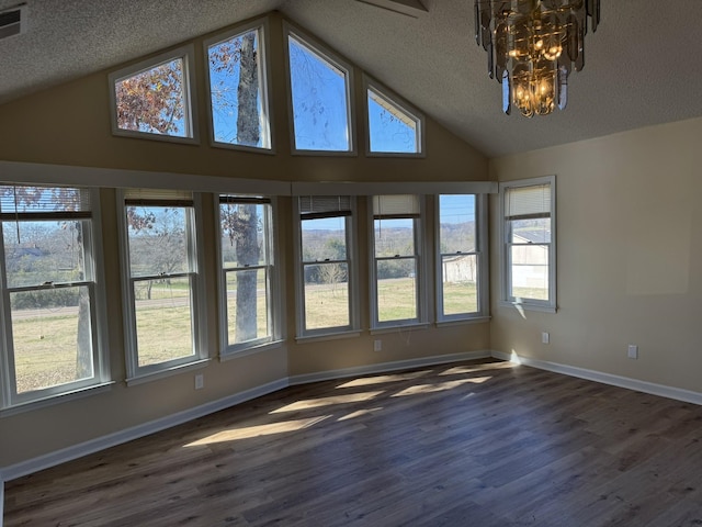 spare room featuring a chandelier, a textured ceiling, dark hardwood / wood-style floors, and high vaulted ceiling