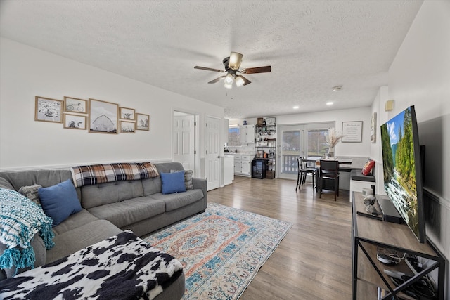 living room with ceiling fan, wood-type flooring, and a textured ceiling