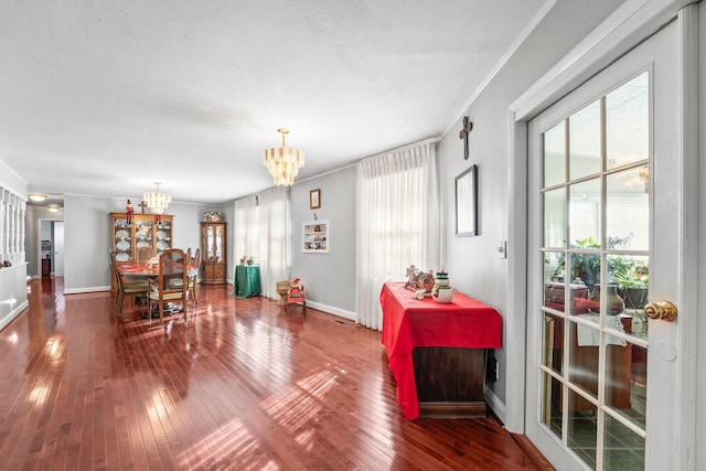 dining room featuring wood-type flooring, a textured ceiling, ornamental molding, and a notable chandelier