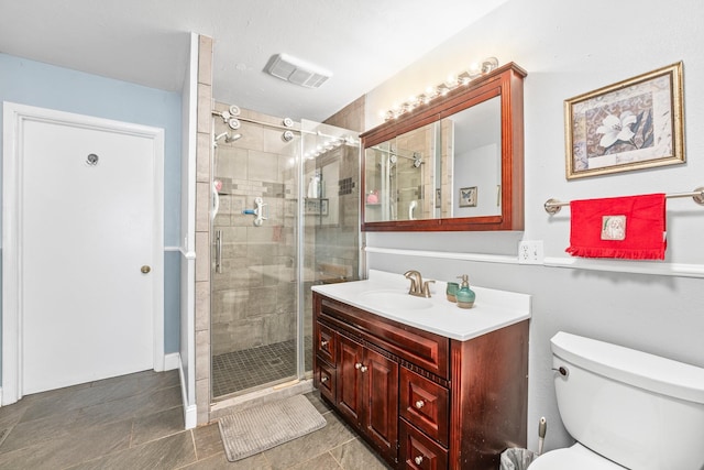 bathroom featuring tile patterned flooring, vanity, a shower with shower door, and toilet