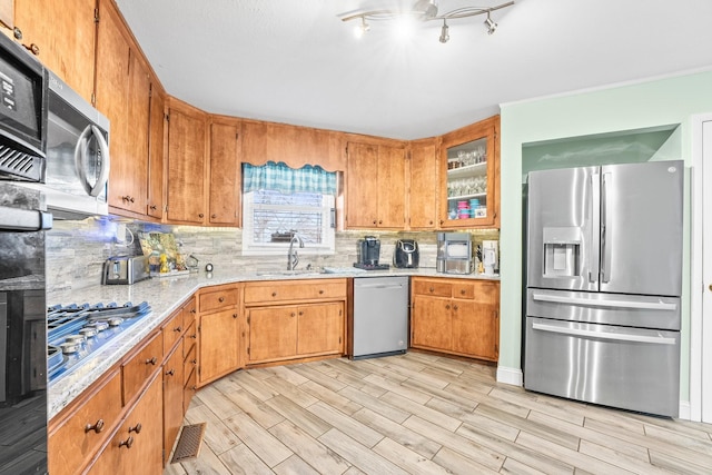 kitchen featuring decorative backsplash, appliances with stainless steel finishes, light hardwood / wood-style flooring, and sink