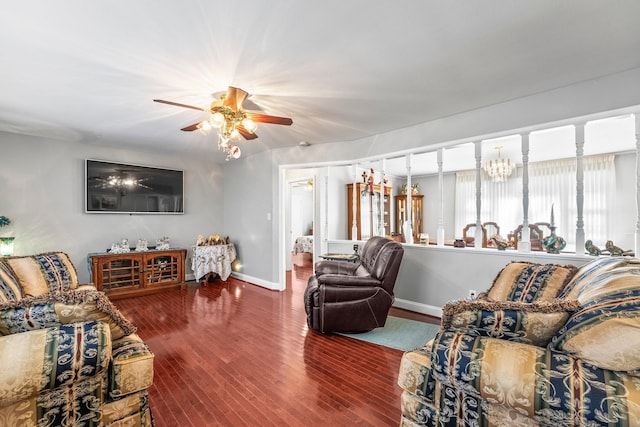 living room with ceiling fan with notable chandelier and dark hardwood / wood-style flooring