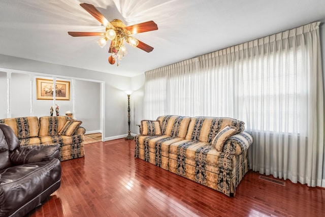 living room featuring ceiling fan, dark wood-type flooring, and a wealth of natural light