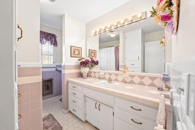 bathroom with tile patterned floors, a fireplace, vanity, and tile walls