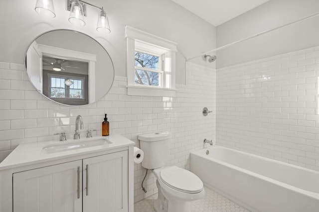 full bathroom featuring tiled shower / bath, tile walls, vanity, ceiling fan, and toilet