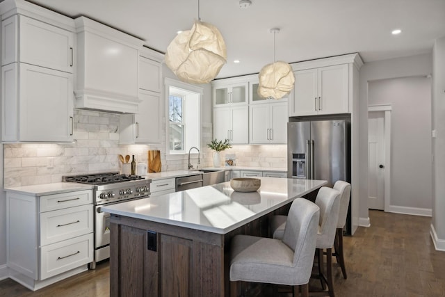 kitchen with appliances with stainless steel finishes, dark wood-type flooring, a center island, white cabinetry, and hanging light fixtures