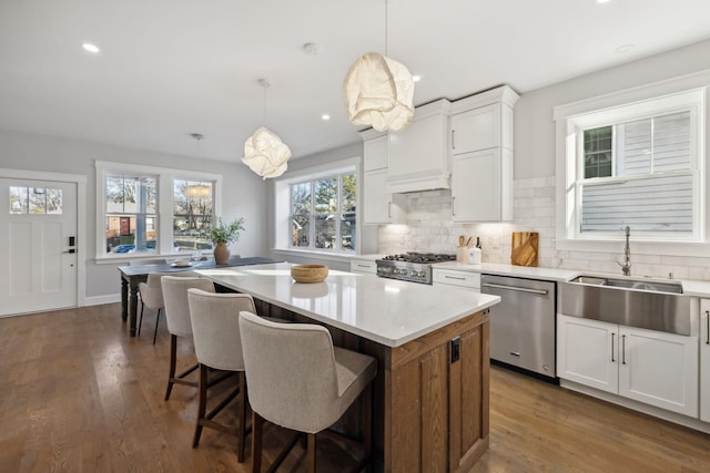 kitchen featuring pendant lighting, dishwasher, stove, a center island, and white cabinets