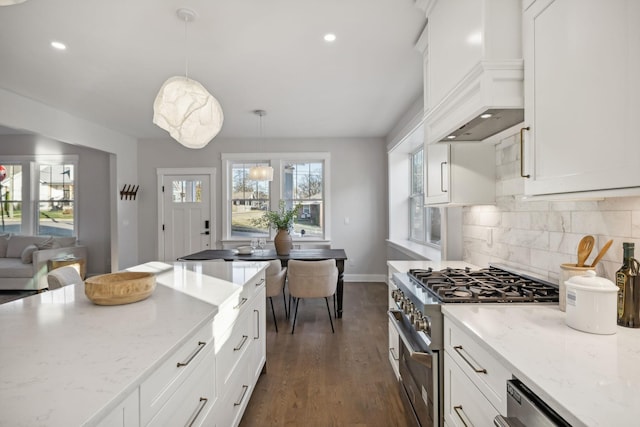 kitchen featuring light stone counters, hanging light fixtures, custom range hood, stainless steel appliances, and white cabinets