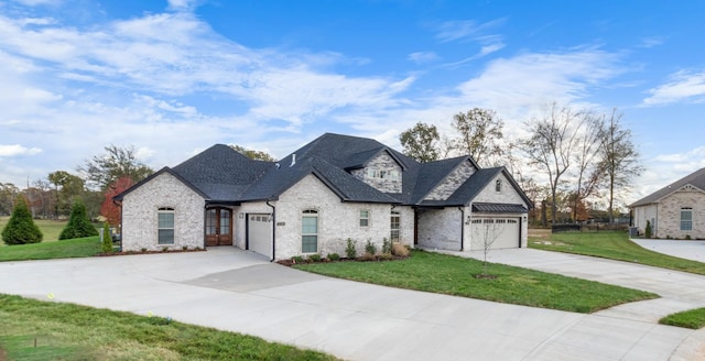 french country inspired facade featuring a garage and a front lawn