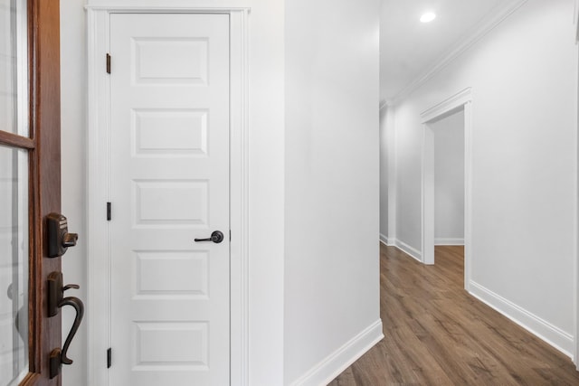 corridor featuring wood-type flooring and ornamental molding