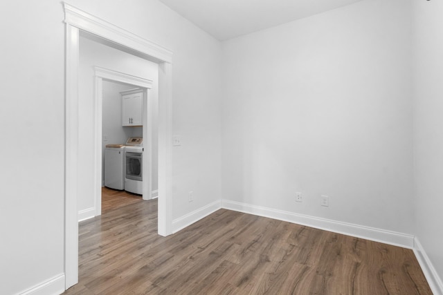 empty room with independent washer and dryer, baseboards, and wood finished floors