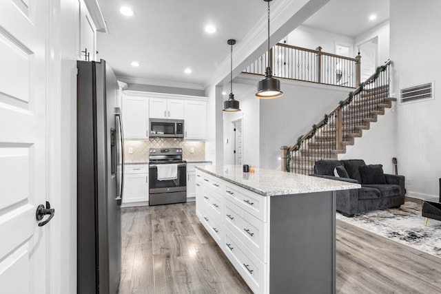 kitchen featuring appliances with stainless steel finishes, white cabinets, visible vents, and light wood-style flooring