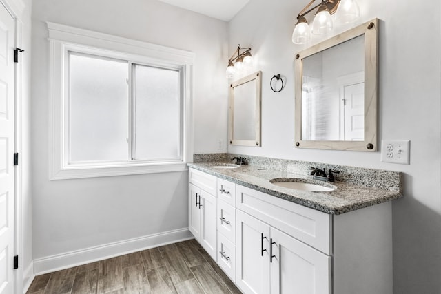 bathroom featuring double vanity, a sink, baseboards, and wood finished floors