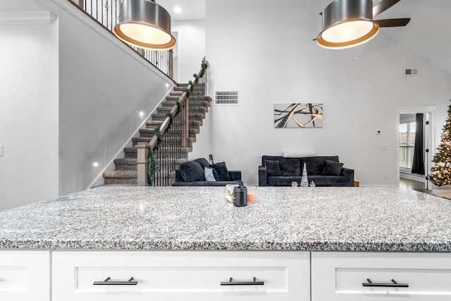 kitchen featuring light stone counters, open floor plan, visible vents, and white cabinetry