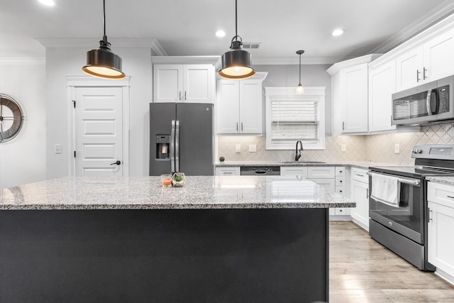 kitchen with light wood-style flooring, a sink, ornamental molding, appliances with stainless steel finishes, and a center island