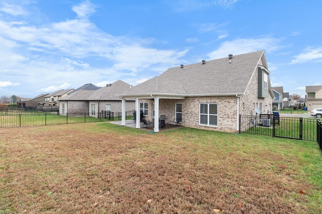 back of house featuring a yard, brick siding, a patio, and a fenced backyard