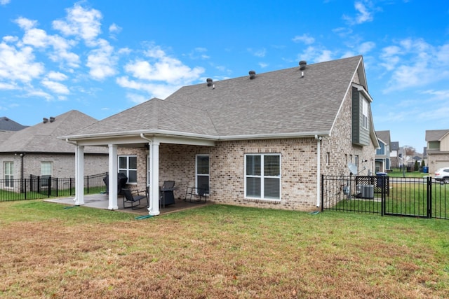 back of property with a patio area, a yard, brick siding, and roof with shingles