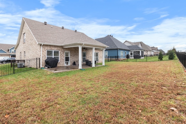 back of house featuring a patio area, a fenced backyard, brick siding, and a yard