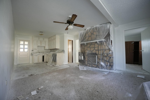 unfurnished living room with ceiling fan, a textured ceiling, and light carpet