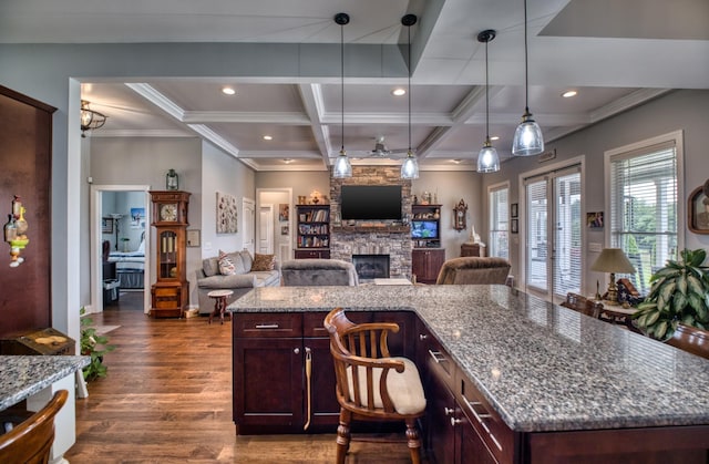 kitchen featuring coffered ceiling, a stone fireplace, light stone counters, beamed ceiling, and dark hardwood / wood-style flooring