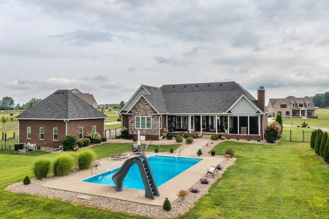 rear view of house featuring a yard, a fenced in pool, a patio area, and a sunroom