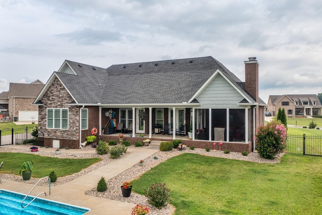 rear view of property featuring a sunroom, a patio area, a fenced in pool, and a yard