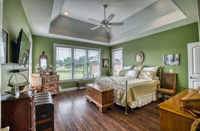 bedroom featuring dark hardwood / wood-style flooring, a tray ceiling, and ceiling fan