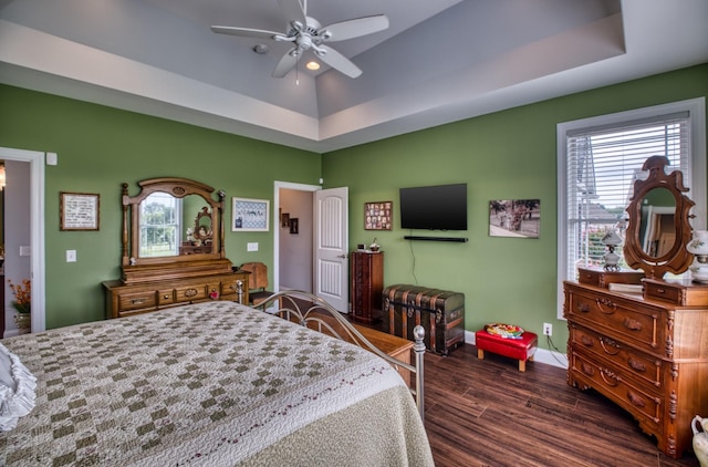 bedroom with a raised ceiling, ceiling fan, and dark hardwood / wood-style flooring