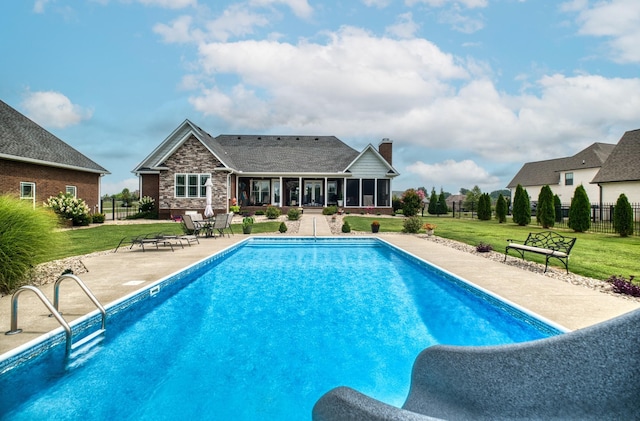 view of swimming pool featuring a sunroom, a patio area, and a yard