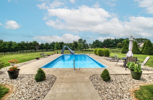 view of swimming pool with a patio, a lawn, and a water slide