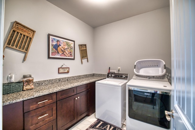 laundry room with cabinets, light tile patterned floors, and washing machine and clothes dryer