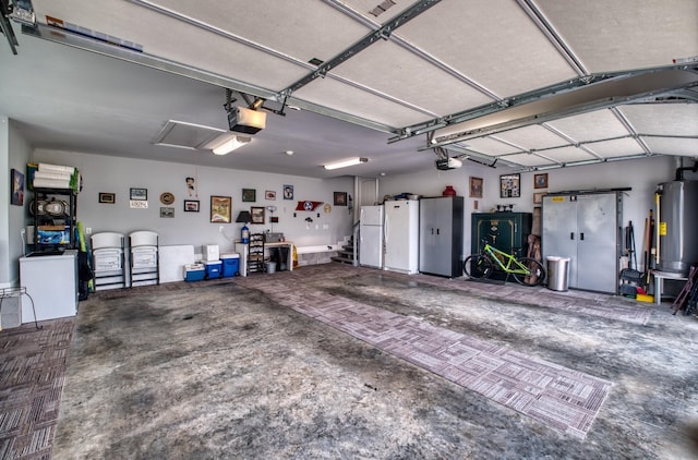 garage featuring white refrigerator, gas water heater, and a garage door opener