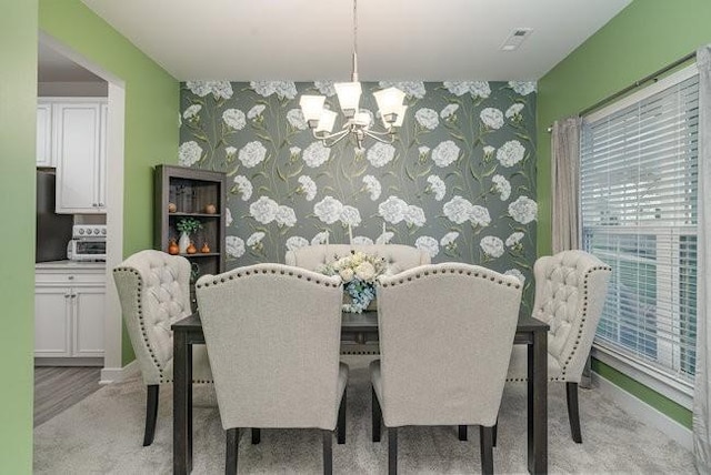 carpeted dining area featuring a chandelier