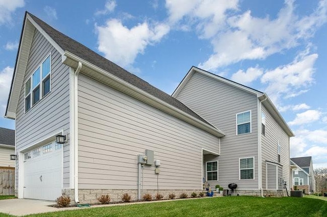 back of house with a yard, a garage, and central air condition unit