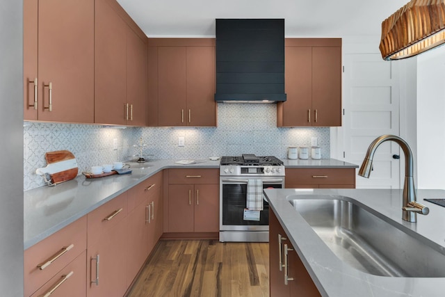 kitchen featuring stainless steel gas range oven, sink, range hood, tasteful backsplash, and dark hardwood / wood-style flooring