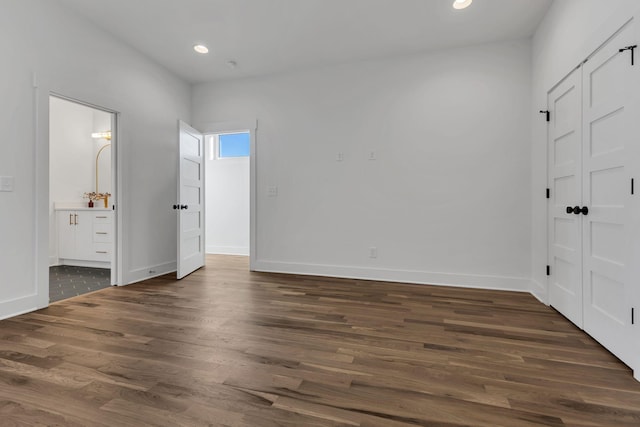 unfurnished bedroom with dark hardwood / wood-style flooring and ensuite bathroom