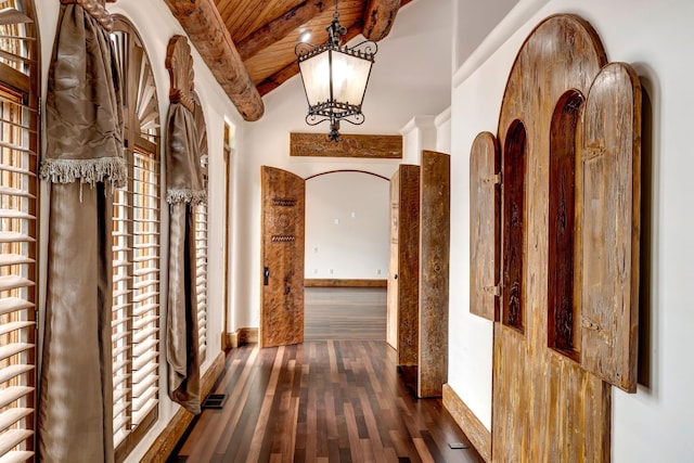 hall with wood ceiling, vaulted ceiling with beams, dark wood-type flooring, and an inviting chandelier