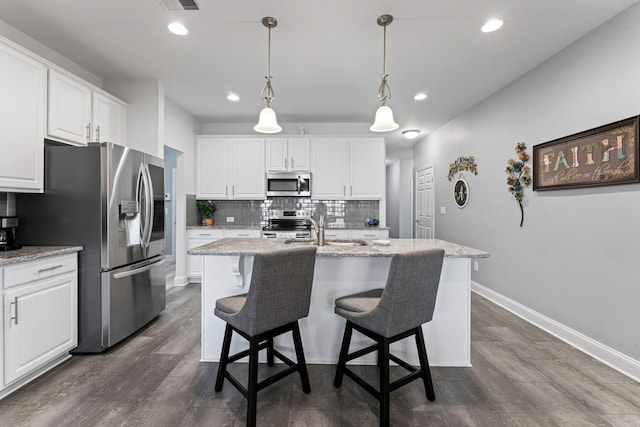 kitchen with white cabinetry, stainless steel appliances, an island with sink, and dark wood-type flooring