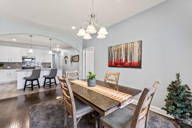 dining room with dark wood-type flooring and an inviting chandelier