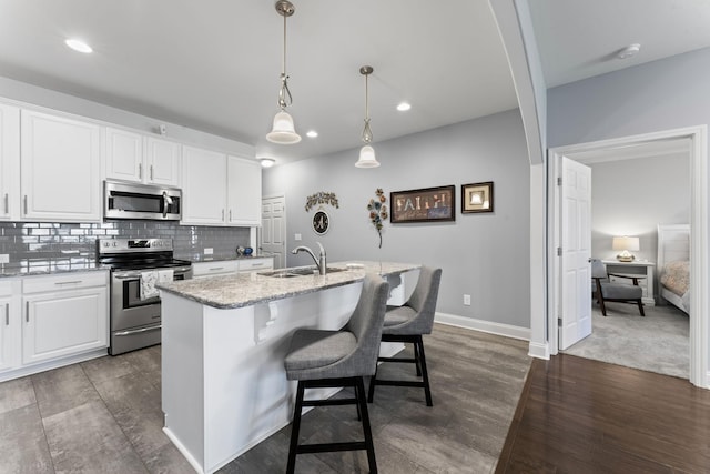 kitchen featuring sink, white cabinetry, stainless steel appliances, and an island with sink