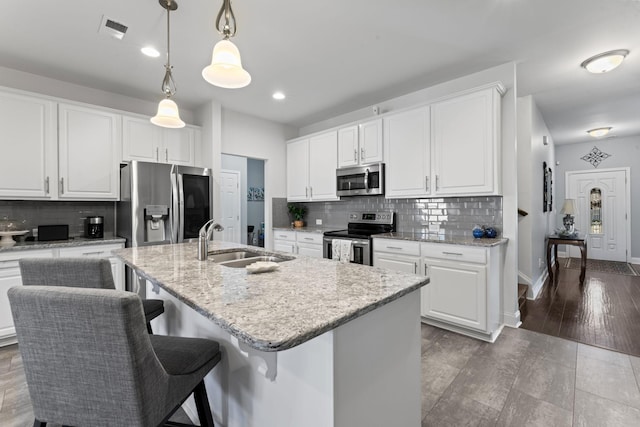 kitchen with white cabinets, stainless steel appliances, and a kitchen island with sink