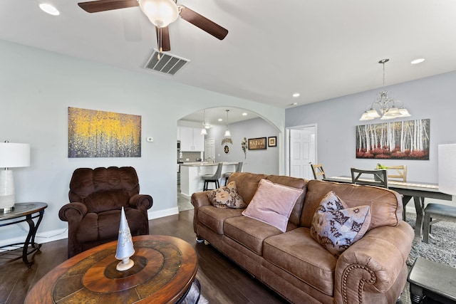 living room featuring ceiling fan with notable chandelier and dark hardwood / wood-style flooring