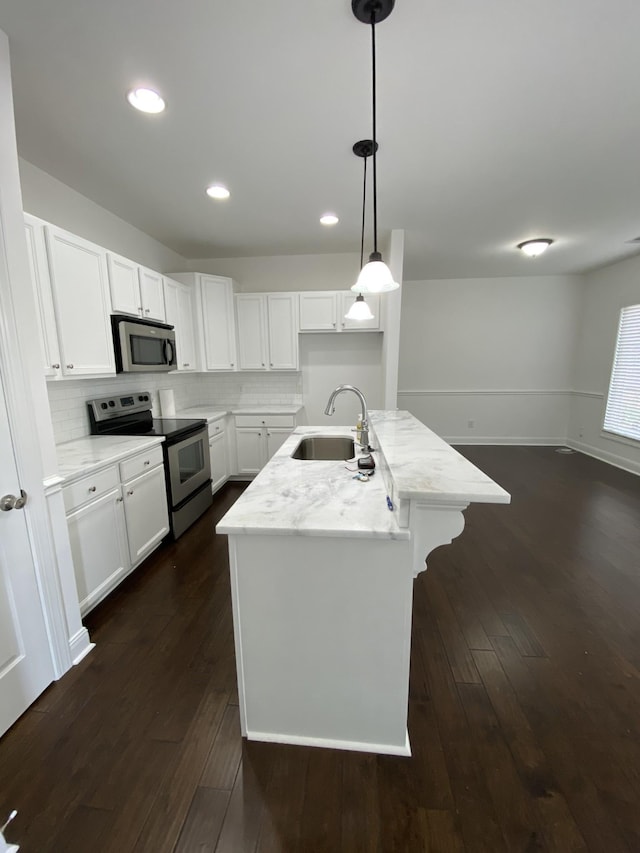 kitchen featuring a kitchen island with sink, sink, decorative light fixtures, dark hardwood / wood-style flooring, and stainless steel appliances