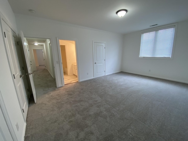 unfurnished bedroom featuring dark colored carpet and ensuite bathroom