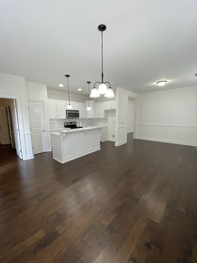 kitchen featuring a center island with sink, white cabinets, hanging light fixtures, appliances with stainless steel finishes, and dark hardwood / wood-style flooring