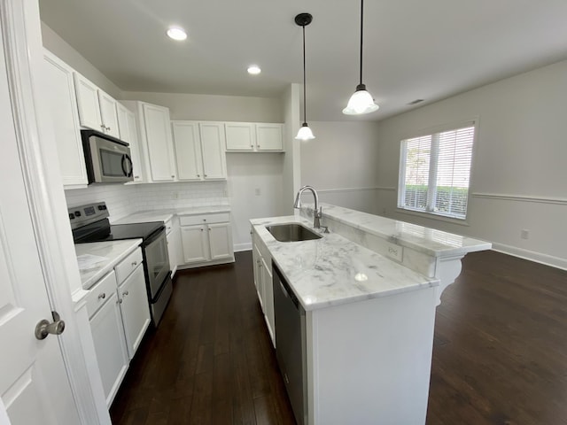 kitchen with stainless steel appliances, sink, pendant lighting, white cabinets, and an island with sink