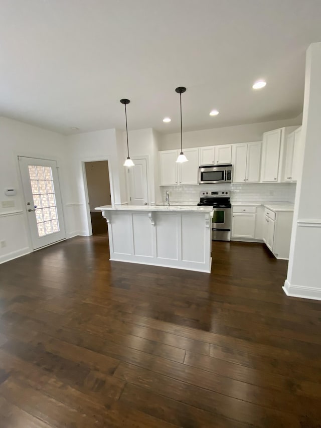 kitchen featuring decorative backsplash, appliances with stainless steel finishes, dark hardwood / wood-style flooring, pendant lighting, and white cabinets